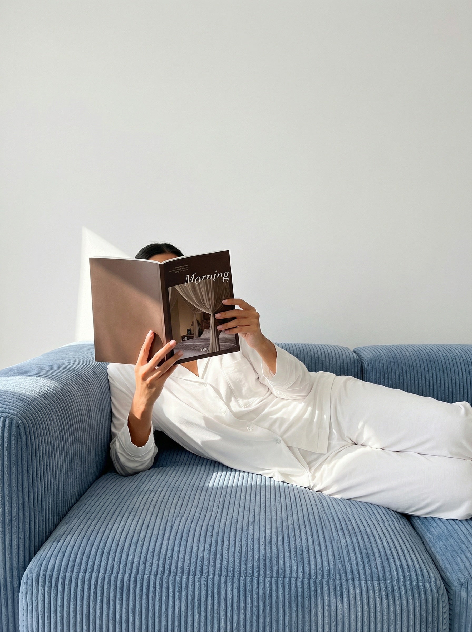 Woman relaxing on a sofa while using the ORA guided morning journal for mindfulness, reflection, and building a daily journaling habit.